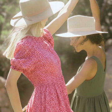 Two women wearing hats outdoors with a blurred natural background